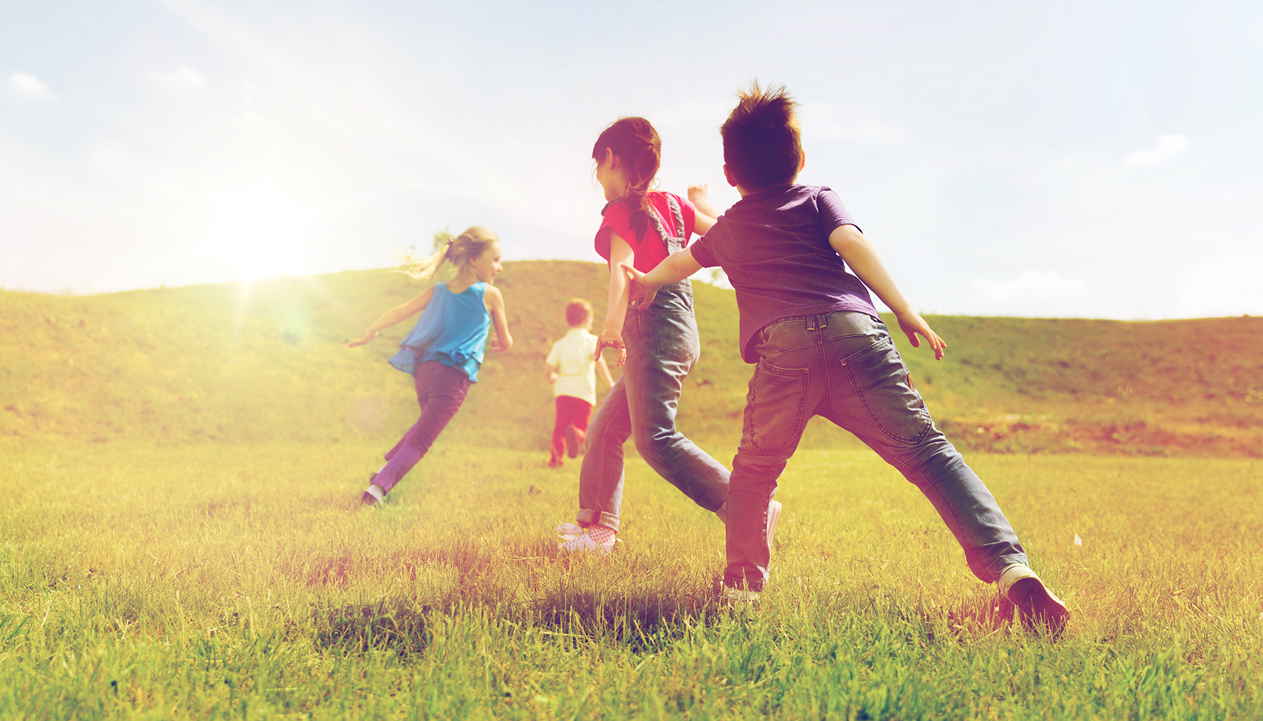 Group of kids playing a game of tag in a grassy field.